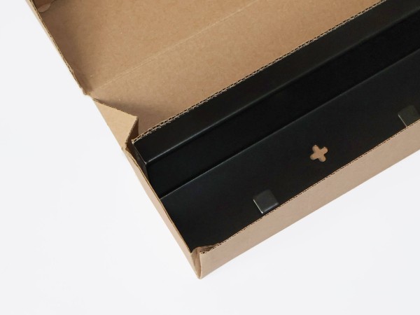 Schwarze Garderobe Commeo passgenau in einem Versandkarton aus Recyclingpappe